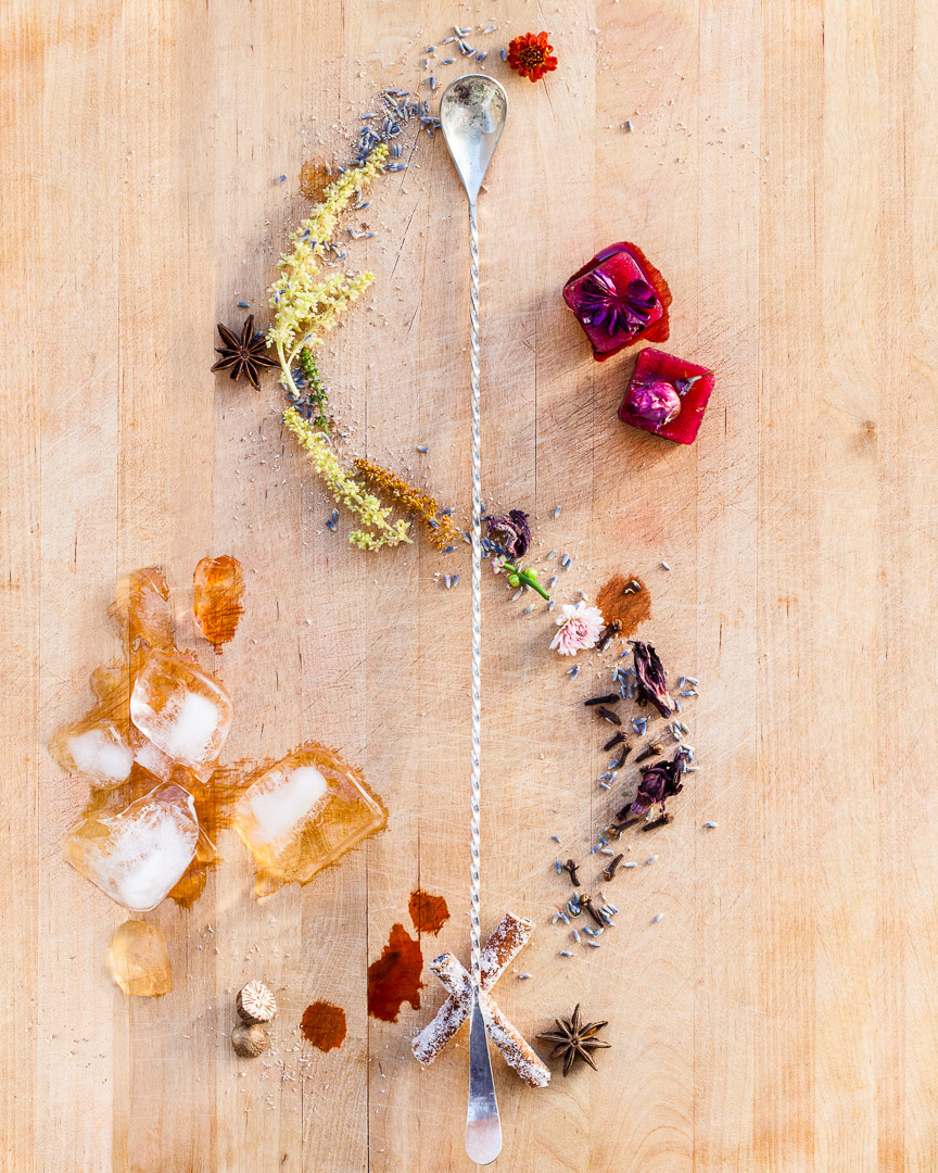 Spoonfuls of Inspiration: Mercedes OBrien - Endless Inspiration Spoonful portrait of Mercedes OBrien titled Endless Inspiration, featuring hibiscus and ginger ice cubes, local pollen, spices, and edible flowers alongside a bar spoon.
